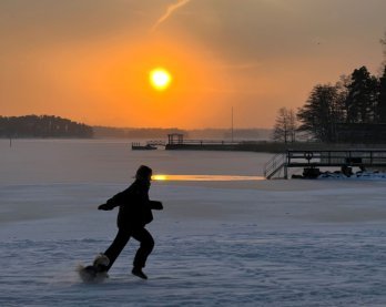 Ihminen juoksee koiran kanssa meren jäällä.